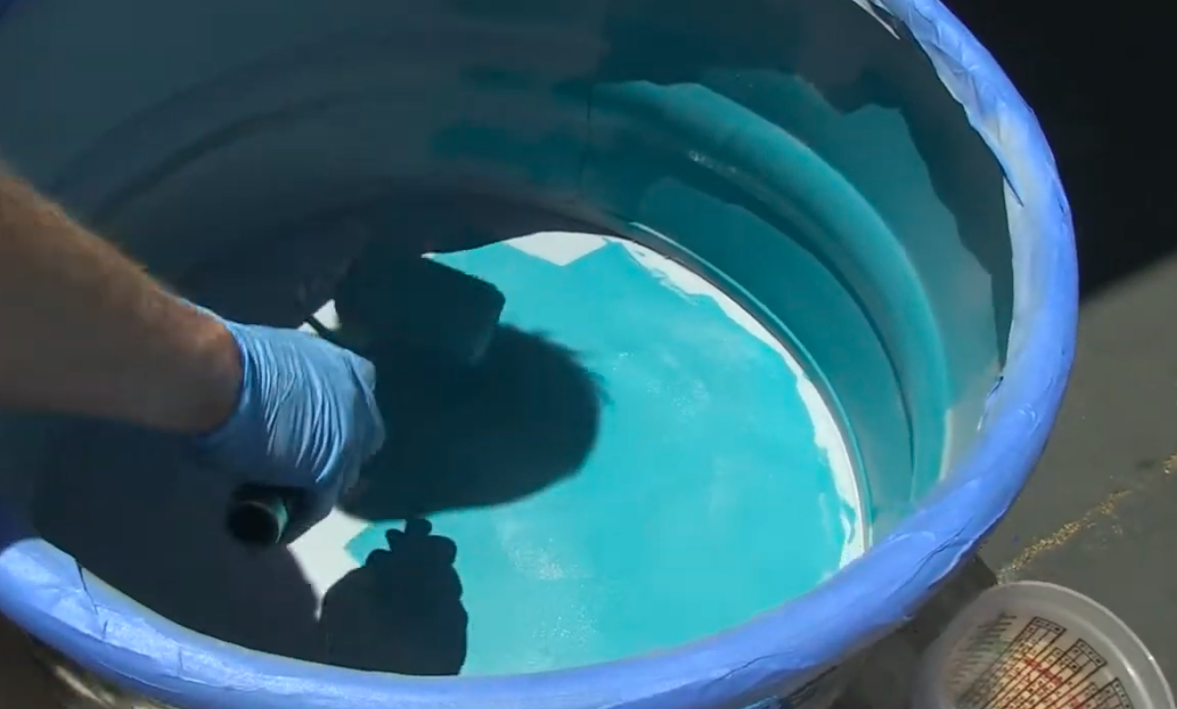 Applying Pond Armor non-toxic epoxy to the interior of a galvanized metal stock tank pool.