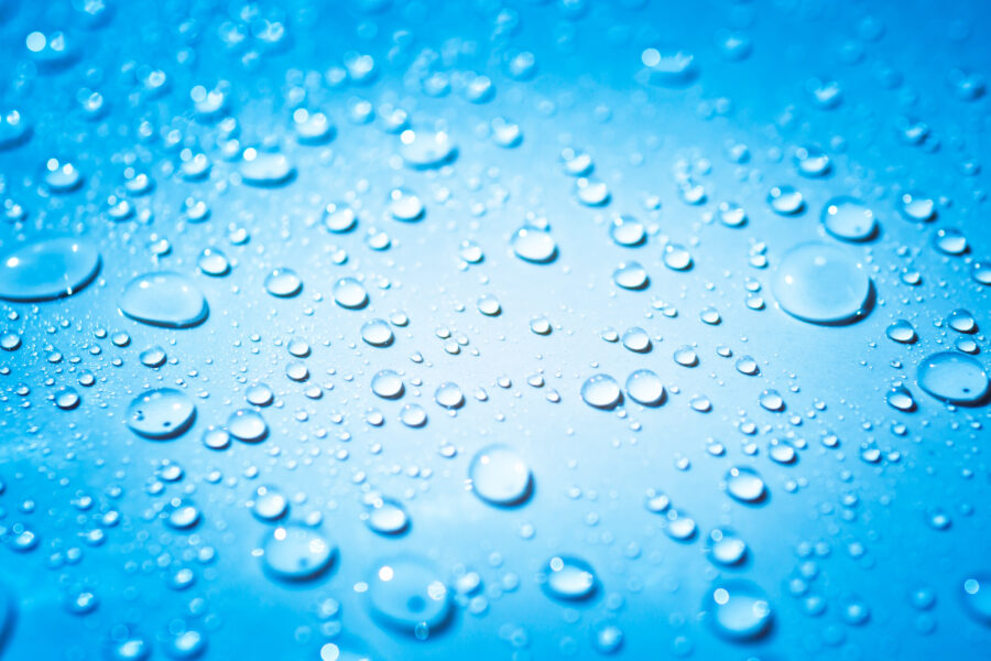 Macro shot of water droplets beading on a smooth, non-porous blue Pond Shield epoxy surface.